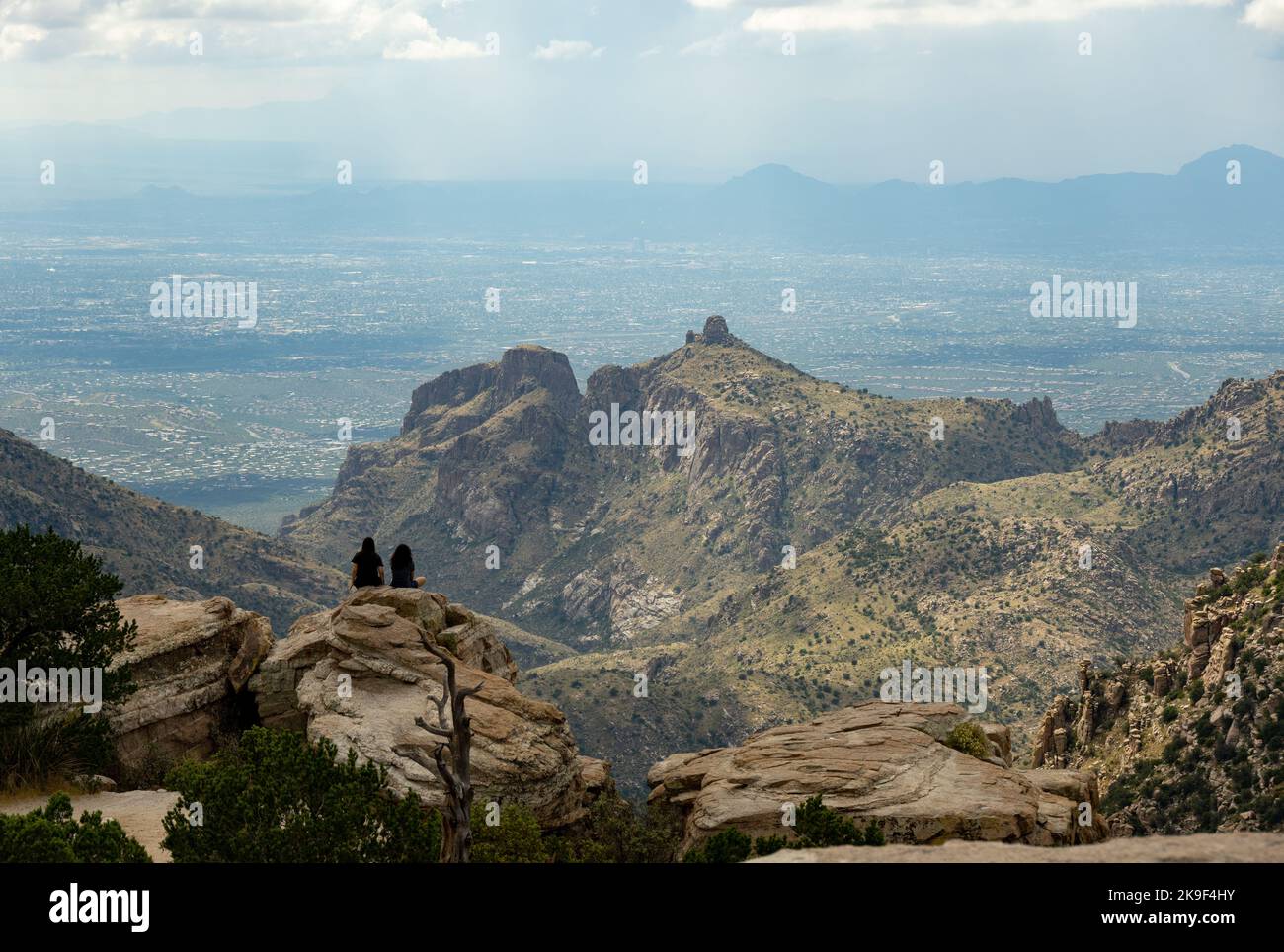 Due giovani donne sedute su alcune rocce che si affacciano sulle montagne di Santa Catalina Foto Stock