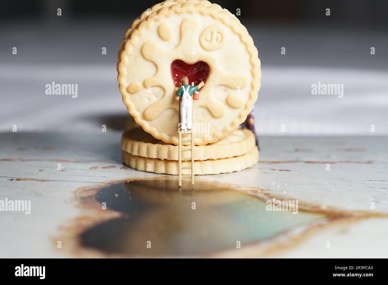 Uomini in miniatura e montagna biscotto, una serie di fotografie che utilizzano persone in miniatura, biscotti alla marmellata e ciottoli che mostrano un mondo di immagini in miniatura. Foto Stock