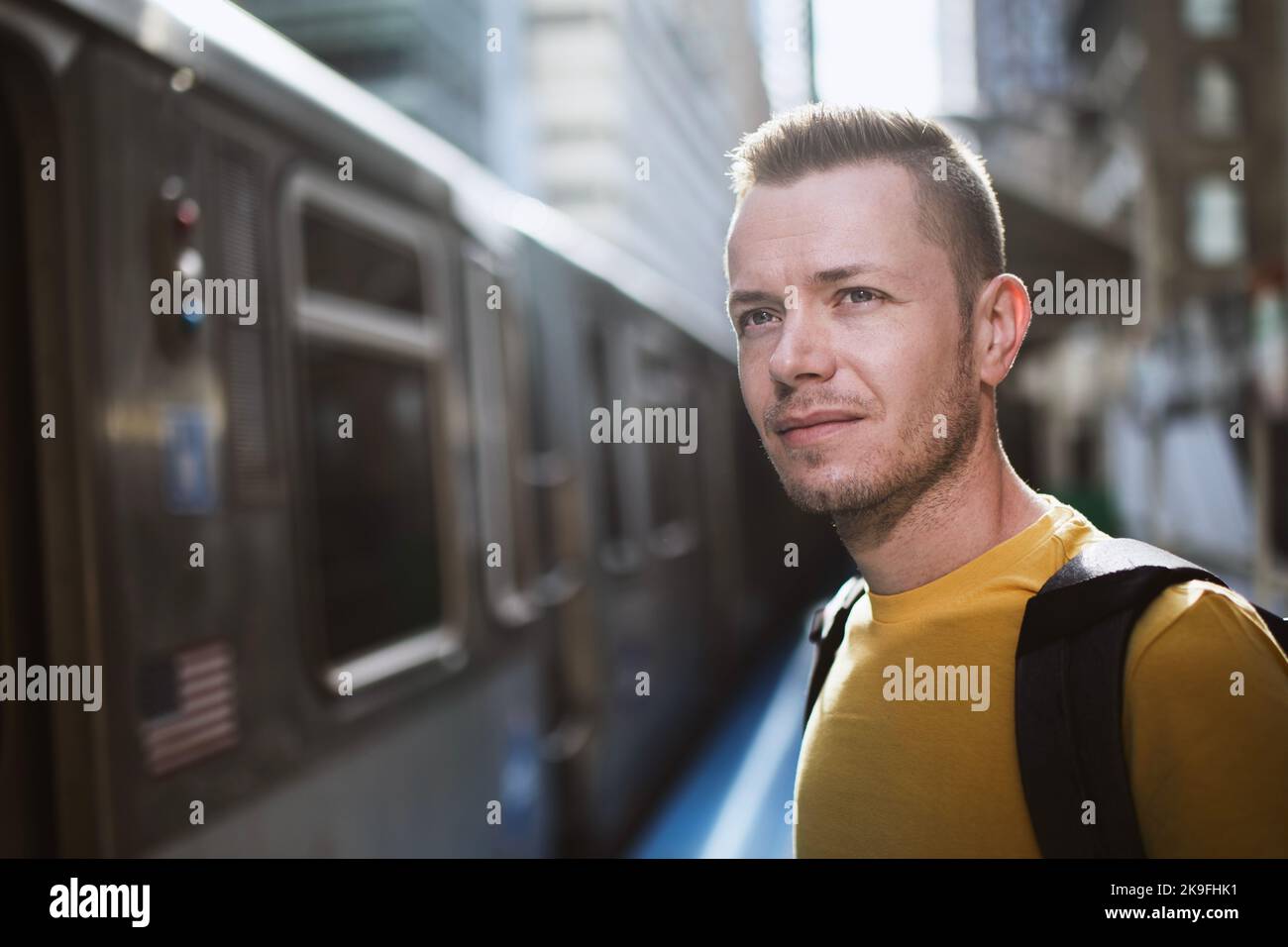Ritratto di uomo in attesa di pendolarismo treno di trasporto pubblico. Passeggero in piedi alla stazione della piattaforma. Foto Stock