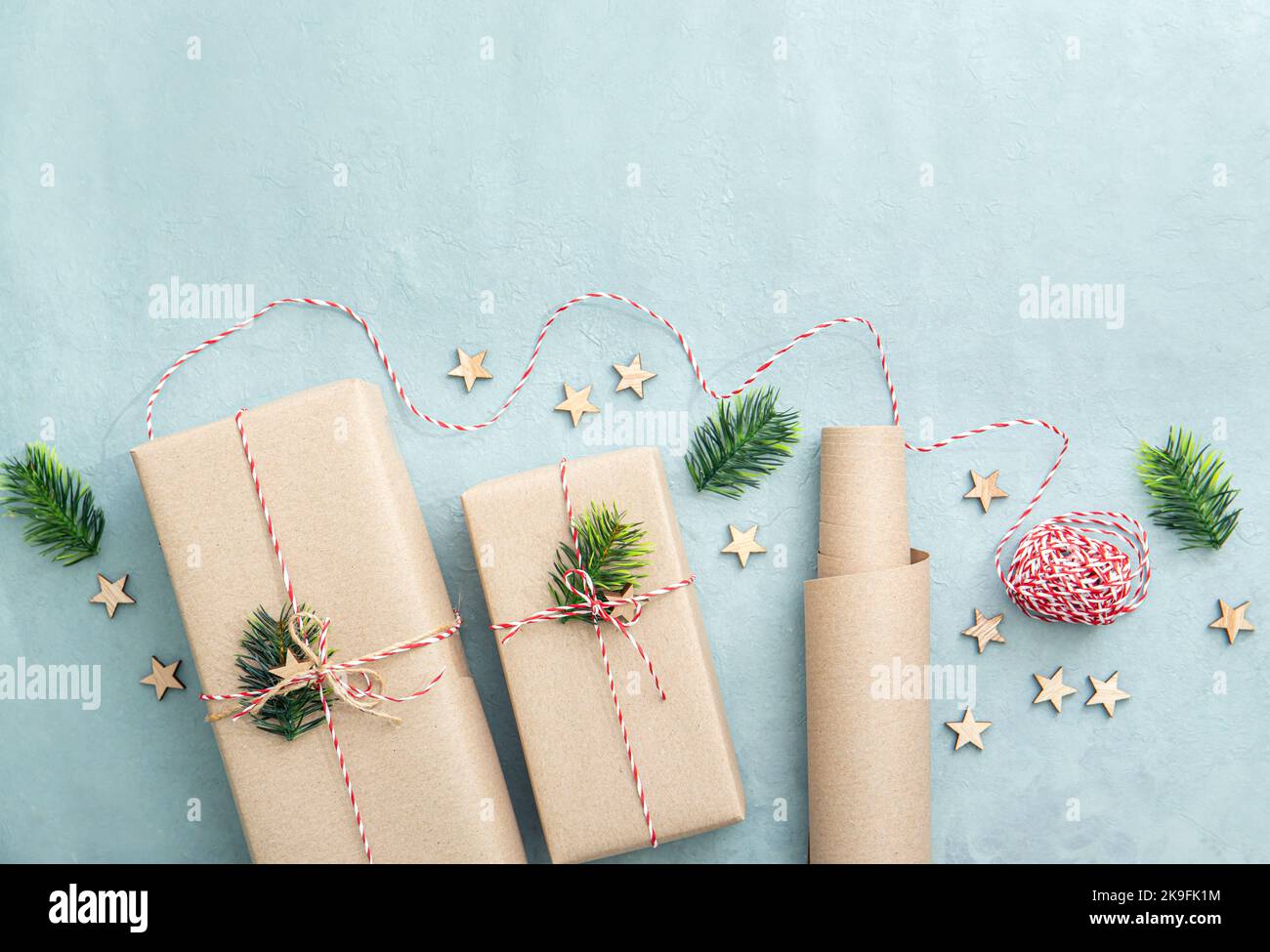 Confezione regalo con carta da imballaggio marrone naturale chiamata carta kraft Sack o carta da sacco. Regali decorati con filo di carta rosso e bianco. Foto Stock