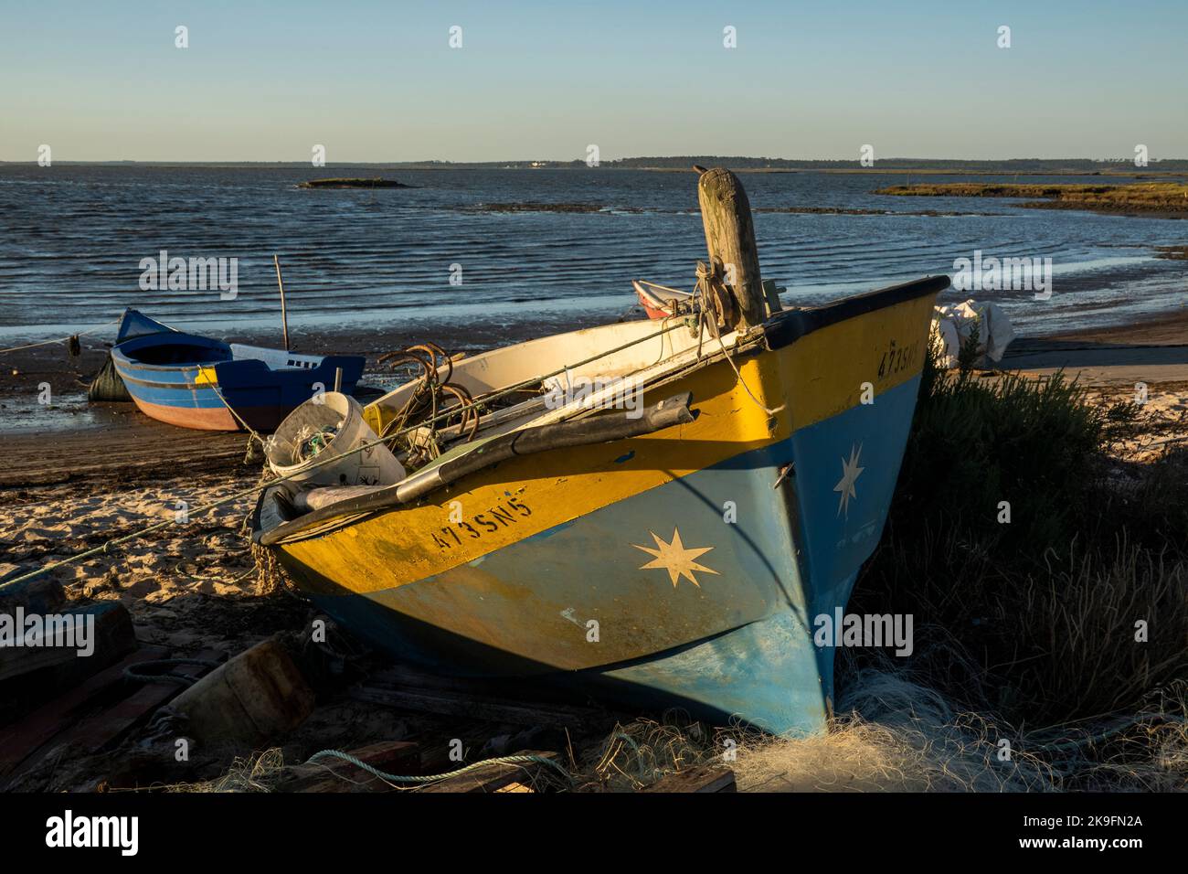 Vista delle vecchie barche da pesca in legno vicino ai moli palafitici situati a Carrasqueira, Portogallo. Foto Stock