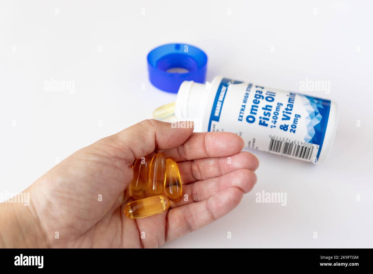 Mano femmina che contiene alcune capsule di olio di pesce omega 3 Foto Stock