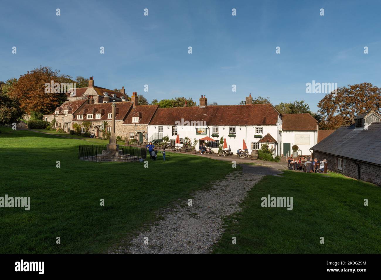 The Village Green a East Dean vicino a Eastbourne, in East Sussex, Inghilterra, Regno Unito, mostrando la Tiger Inn Public House nel tardo pomeriggio luce del sole autunnale. Foto Stock