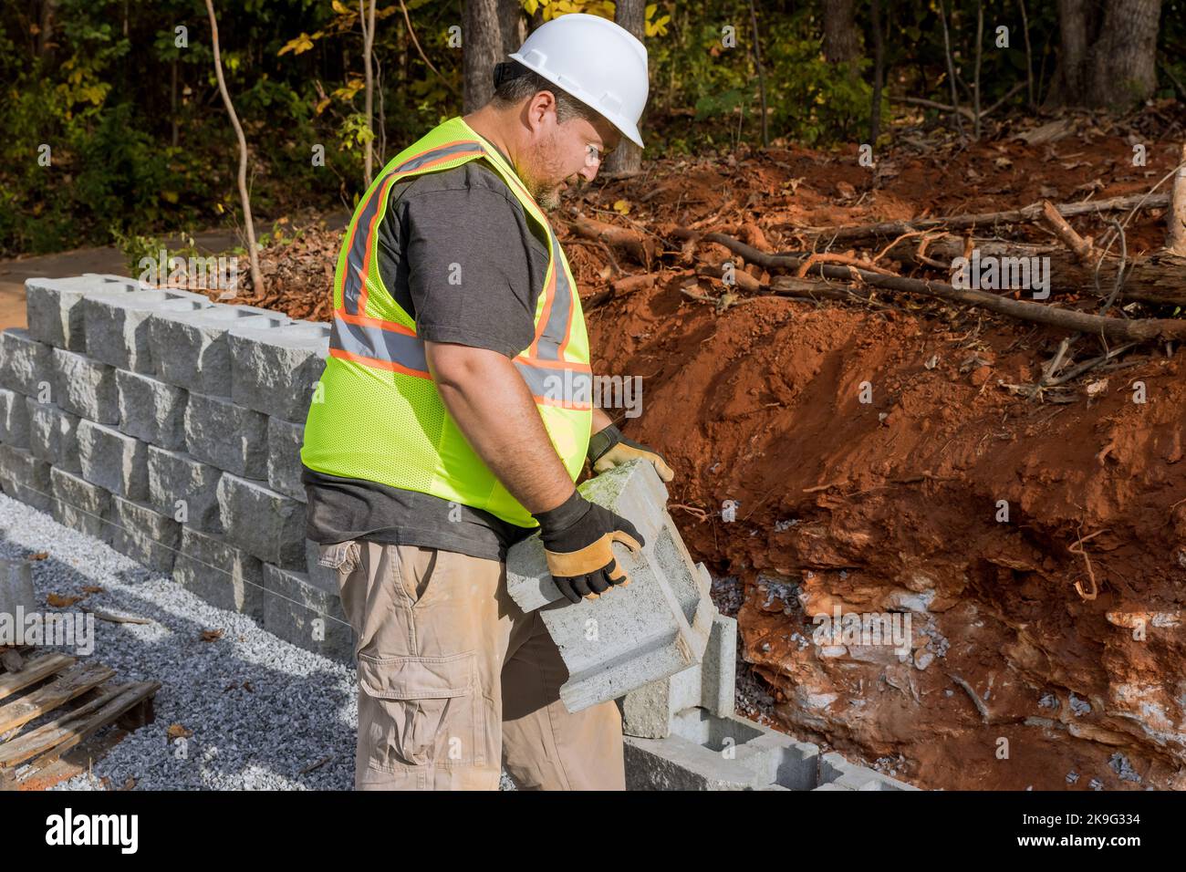 Mentre l'appaltatore stava installando la parete di ritegno di blocco grande di nuova costruzione nel cantiere Foto Stock