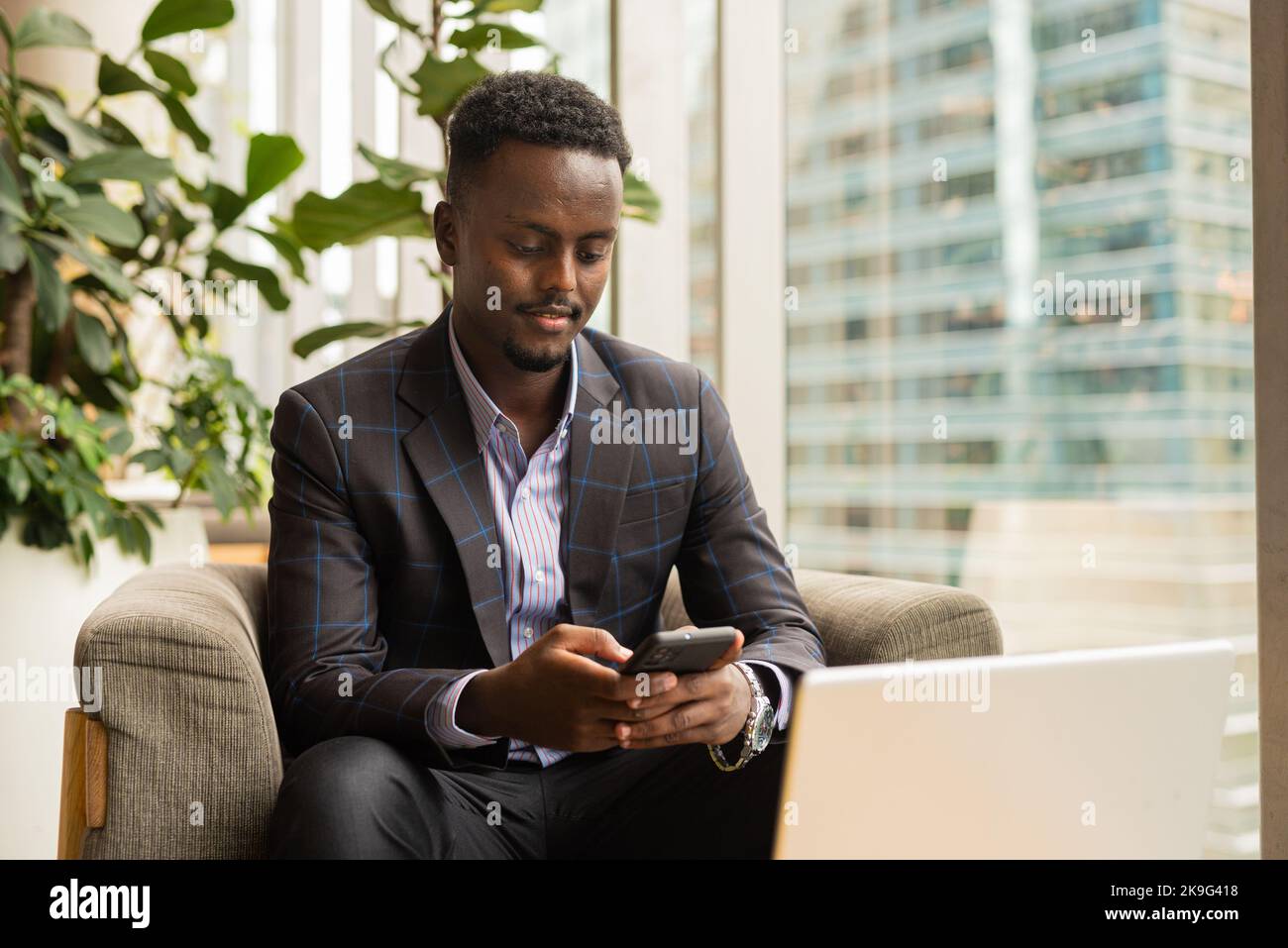 Ritratto di un uomo d'affari africano seduto in una caffetteria utilizzando un computer portatile Foto Stock