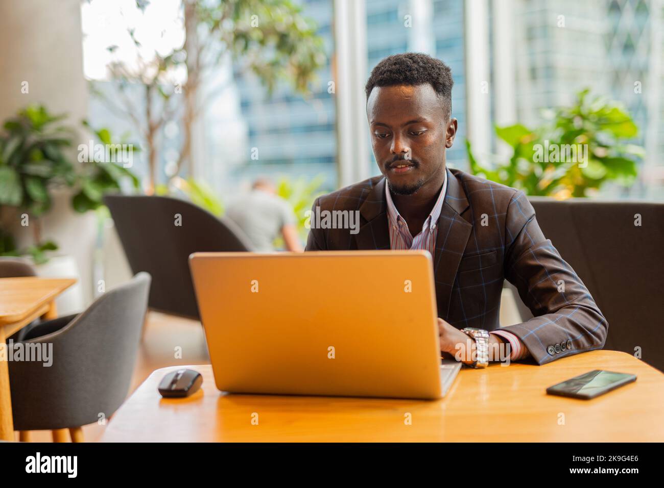 Uomo d'affari africano che usa un computer portatile al bar Foto Stock