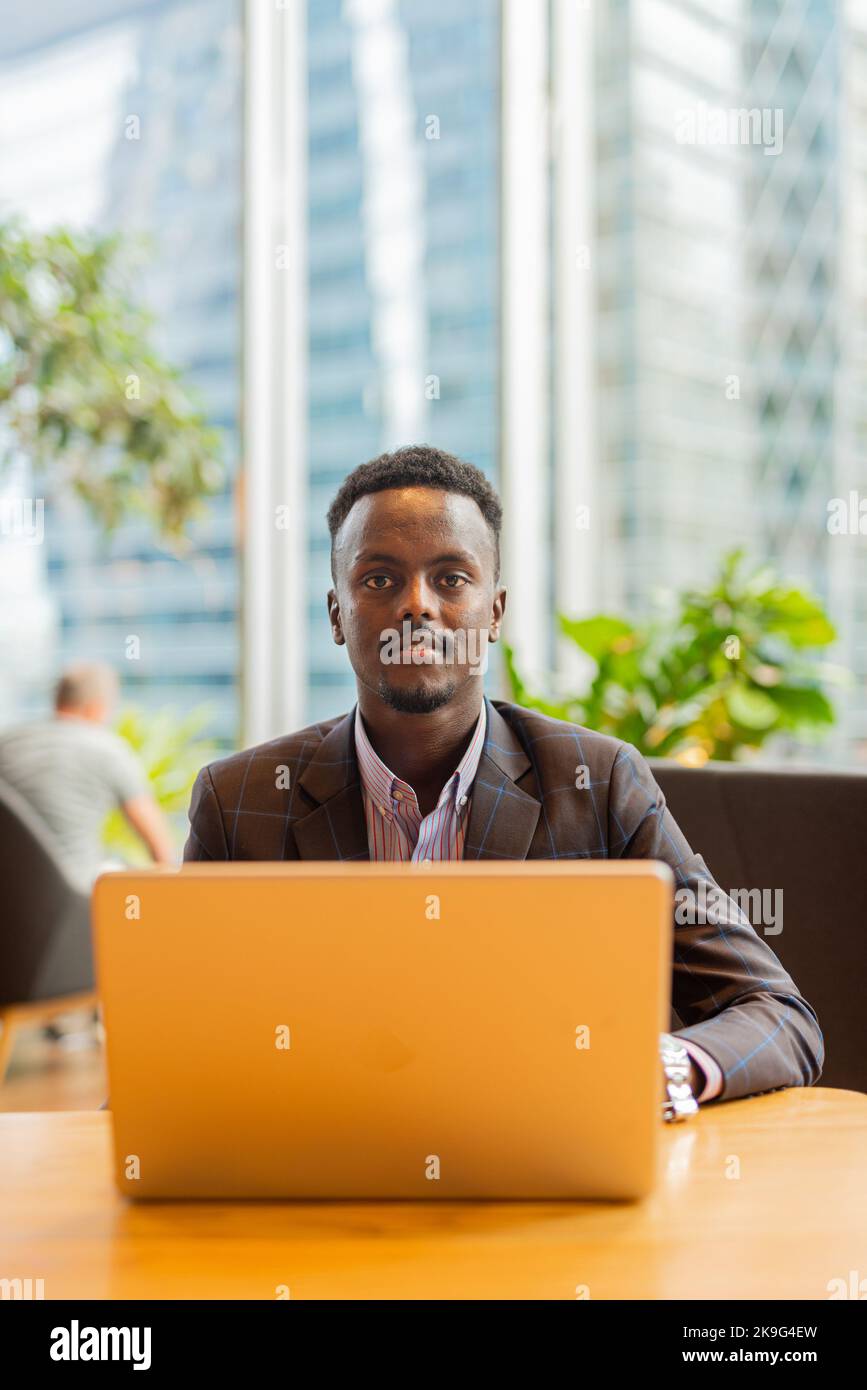 Uomo d'affari africano che usa un computer portatile al bar Foto Stock