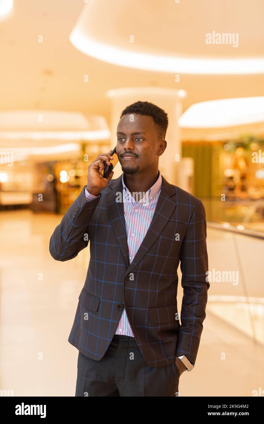 Ritratto di bell'uomo d'affari africano che utilizza il telefono cellulare Foto Stock
