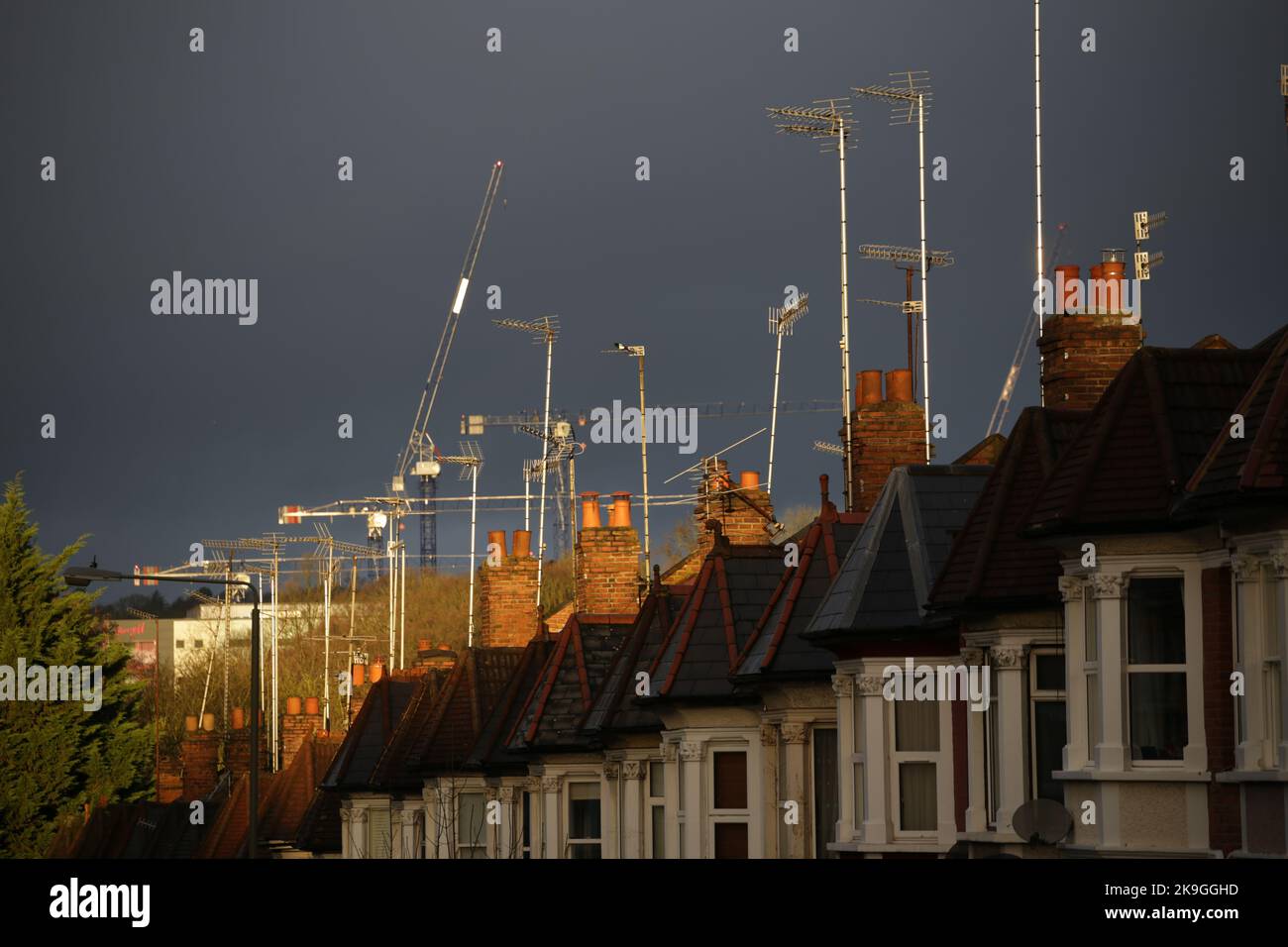 Una scena urbana di TV ariels, tetti, camini e case terrazzate contro un grigio scuro tempestoso e minaccioso cielo.luce intensa aggiunge al dramma Foto Stock