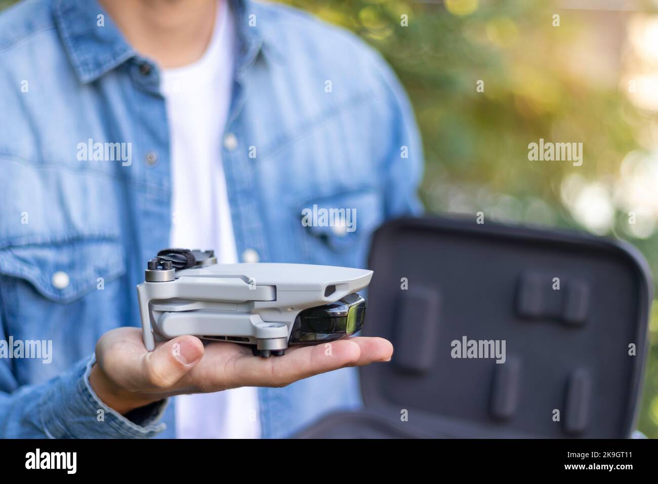 Vista ravvicinata selettiva di un giocattolo ripiegato con telecomando in elicottero appoggiato sulle mani di un ragazzo irriconoscibile Foto Stock