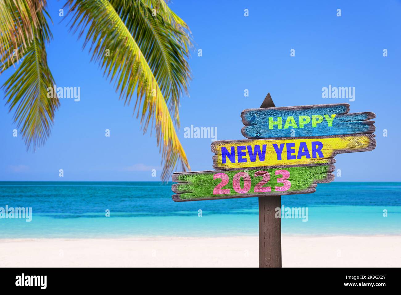 Hapy nuovo anno 2023 scritto su indicazioni stradali, sfondo spiaggia tropicale, viaggio e biglietto di auguri per il turismo Foto Stock