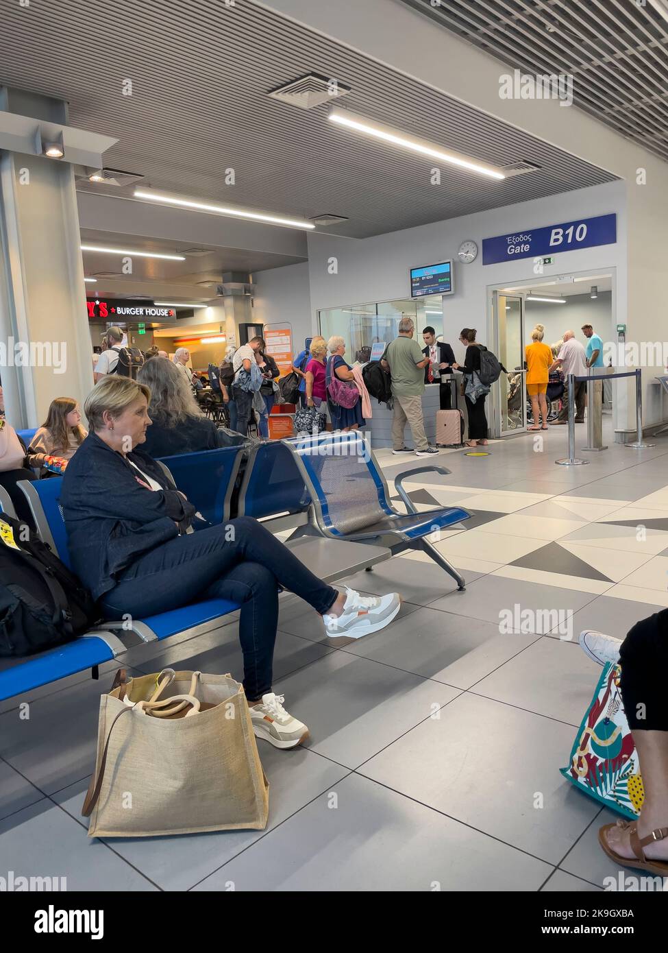 Candia, Creta, Grecia. 2022. I passeggeri che si imbarcheranno e attendono di imbarcarsi su un volo dalla porta d'imbarco all'aeroporto di Heraklion, Creta Foto Stock