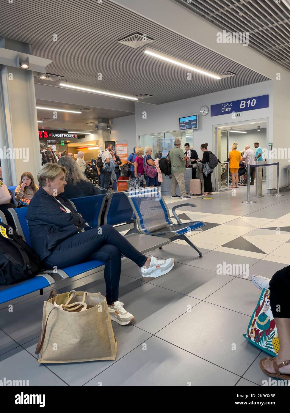 Candia, Creta, Grecia. 2022. I passeggeri che si imbarcheranno e attendono di imbarcarsi su un volo dalla porta d'imbarco all'aeroporto di Heraklion, Creta Foto Stock