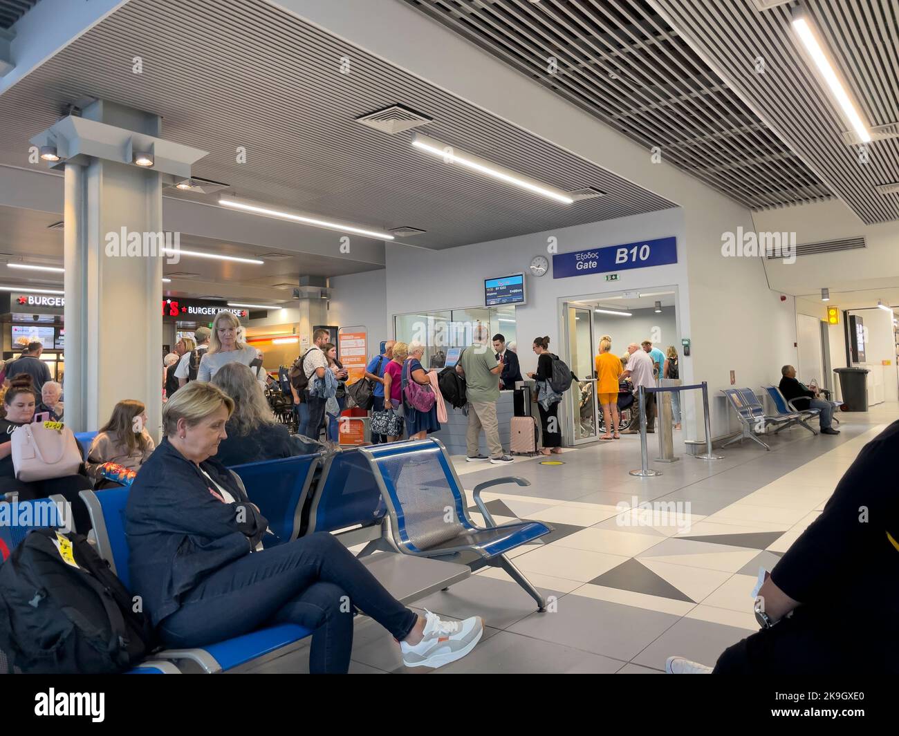 Candia, Creta, Grecia. 2022. I passeggeri che si imbarcheranno e attendono di imbarcarsi su un volo dalla porta d'imbarco all'aeroporto di Heraklion, Creta Foto Stock