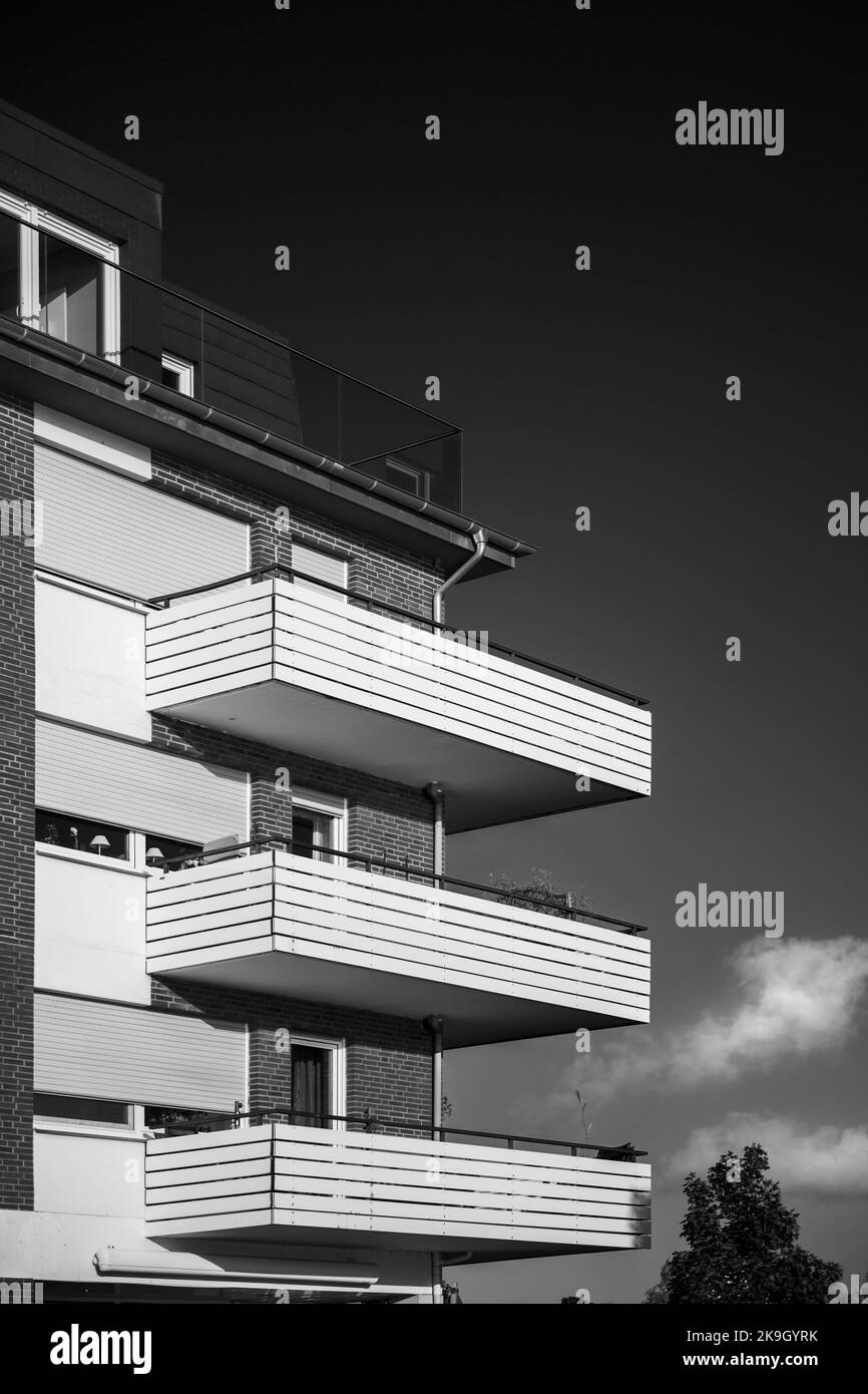 Vista di un edificio residenziale in mattoni con balconi ad angolo di fronte ad un cielo nuvoloso in bianco e nero. Foto Stock