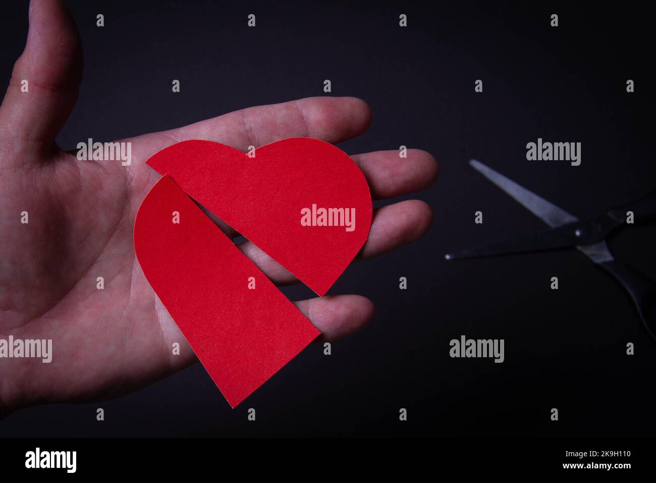 Cuore rotto. Divorzio di una coppia sposata. Matrimonio rotto. Cuore in mano e forbici. Foto Stock