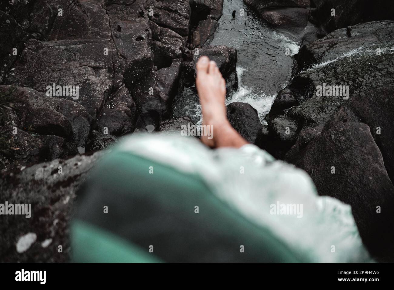 piede penzolante sopra le rocce nel fiume Foto Stock