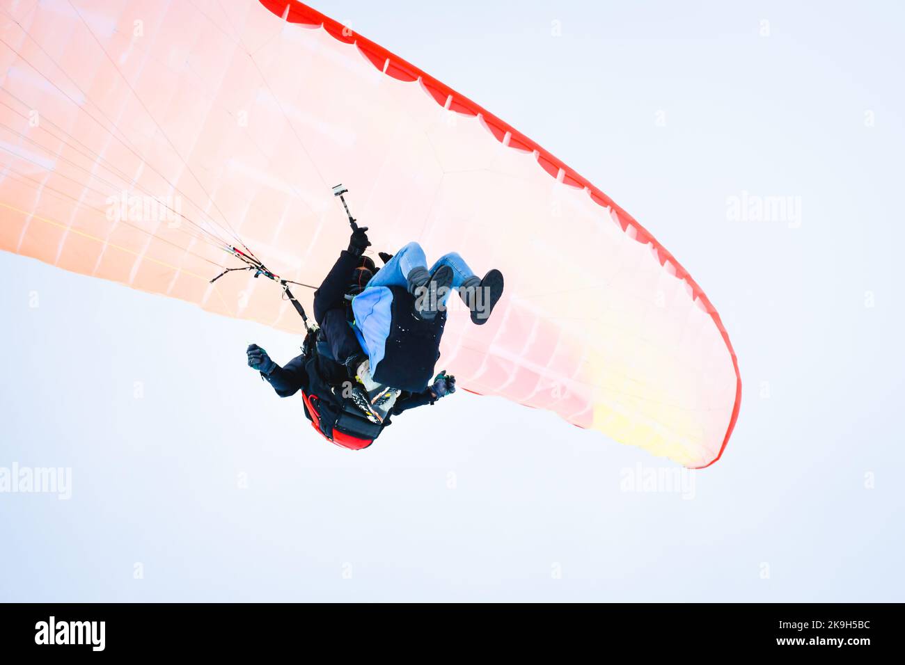 Sotto l'istruttore con il turista fare parapendio in tandem, mentre filmare esperienza in cielo limpido buone condizioni meteorologiche in inverno Gudauri sci Foto Stock