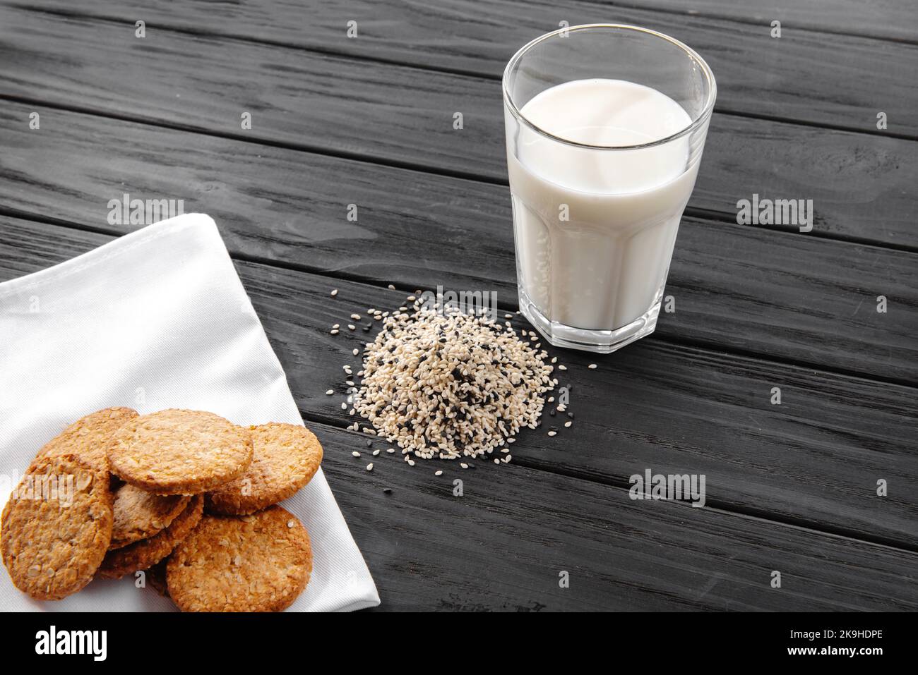 Latte di sesamo e semi di sesamo in una ciotola su sfondo grigio. Spazio di copia. Un sano vegetariano pianta-based alternativa sostituto del latte Foto Stock