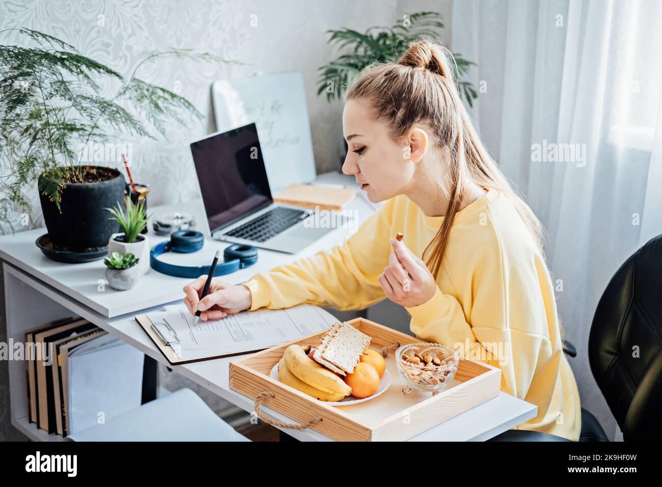 Lavoro flessibile, lavoro flessibile. Giovane donna freelance che lavora in ufficio con computer portatile e documenti. Orario di lavoro flessibile. Foto Stock