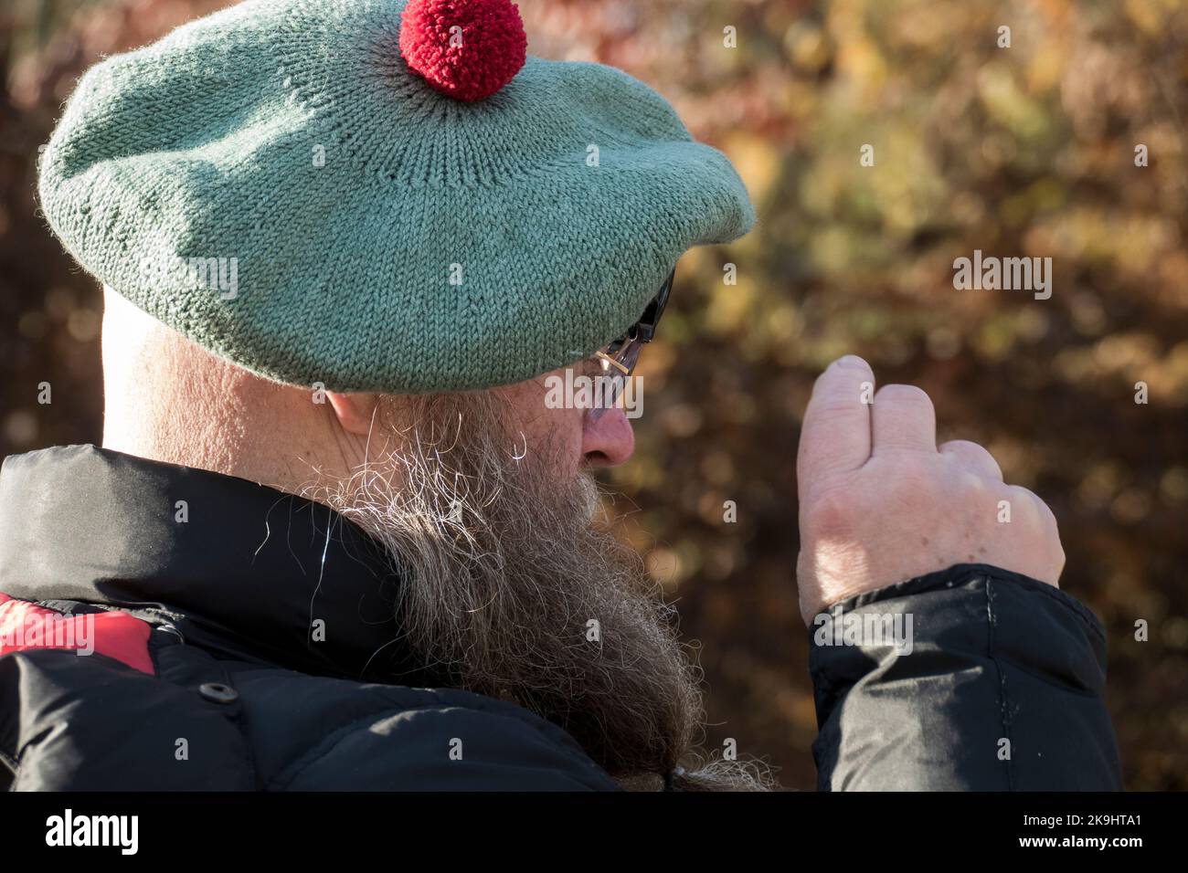 Mann mit langem Bart und Schottenmütze fotografiert mit seinem handy Foto Stock