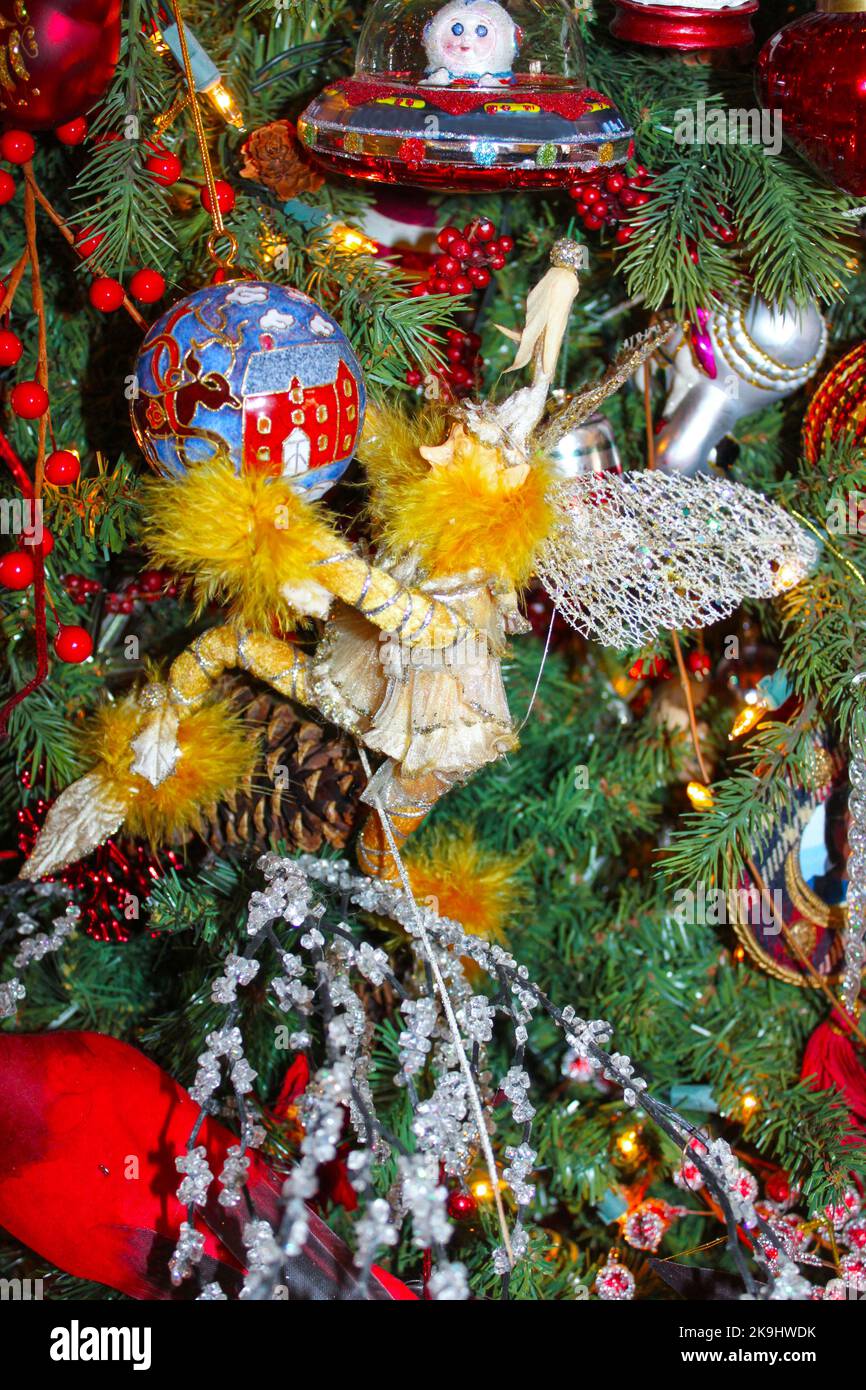 Fiaba che tiene ornamento di Natale sotto ornamento di spaceman su albero eclettico di festa Foto Stock