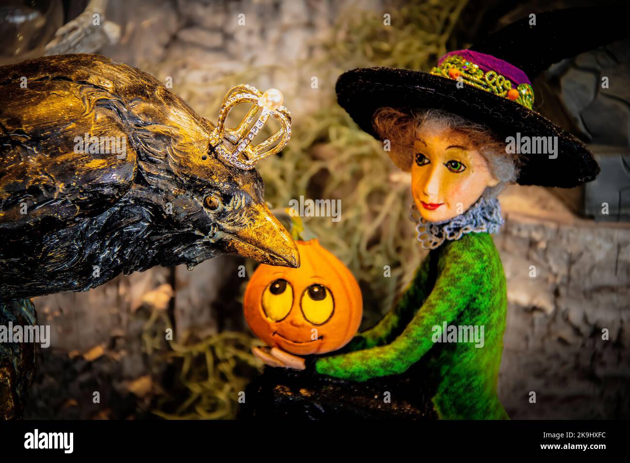 Grande corvo nero con corone si presenta su cute strega con zucca in Halloween decorazione secenaio-sfondo sfocato Foto Stock