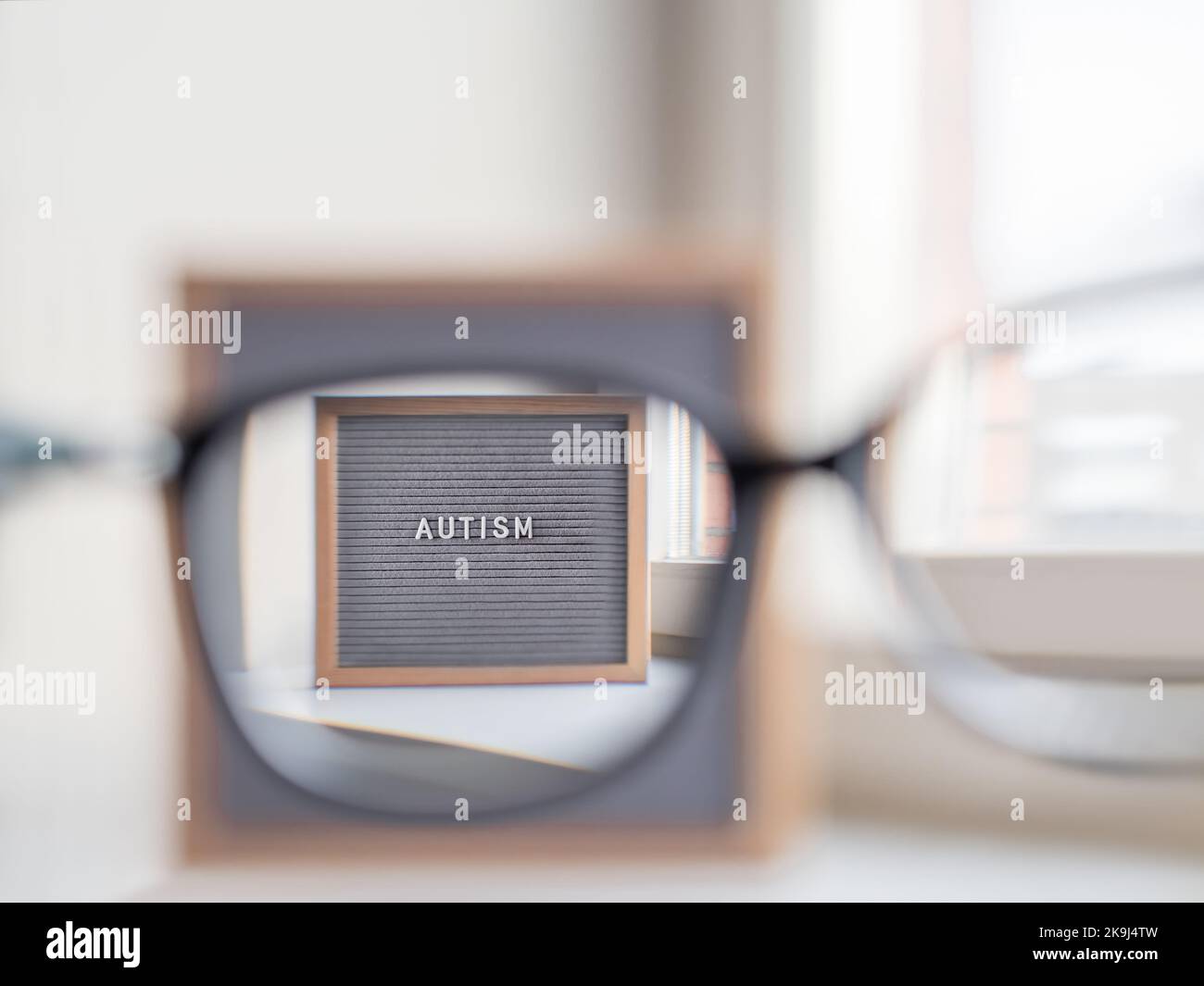 Cartoncino grigio con autismo parola. Vista attraverso gli occhiali sulla diagnosi medica che di solito ha fatto in infanzia. Foto Stock