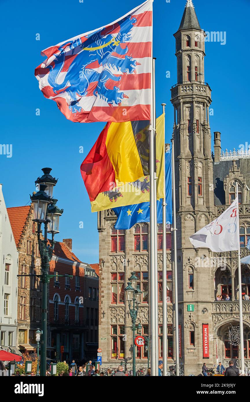 Bandiere che volano nel Markt, Piazza del mercato, Bruges con la bandiera a strisce rosse e bianche di Bruges prominente. Foto Stock