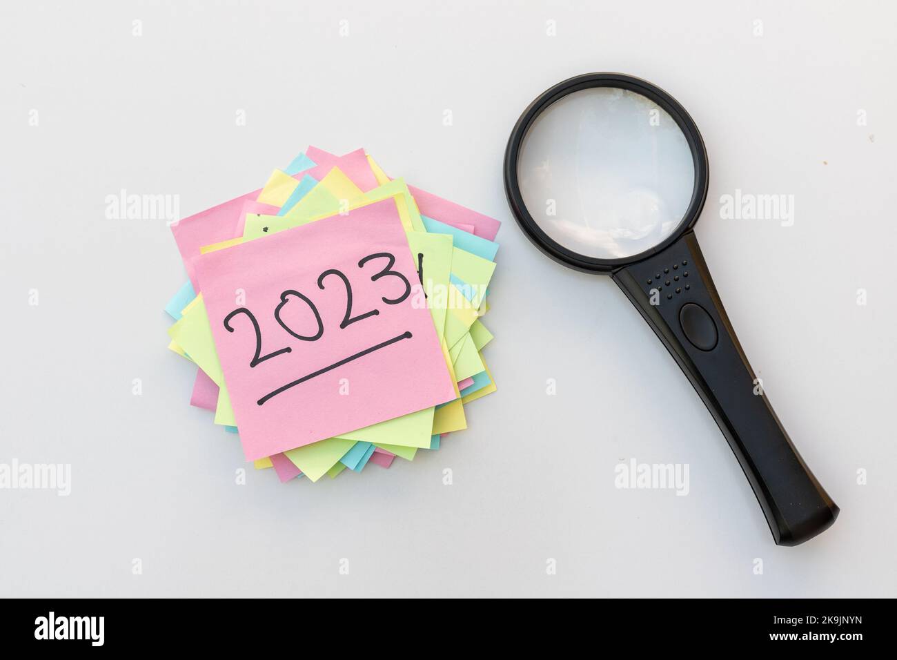 Ricerca per il nuovo anno 2023 con lente di ingrandimento. Concettuale manoscritto 2023 su sticky note Foto Stock