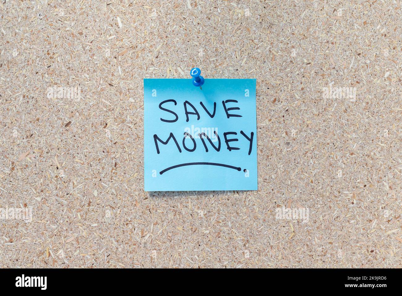 Risparmia denaro scritto a mano su uno sfondo di sughero con spazio per la copia Foto Stock
