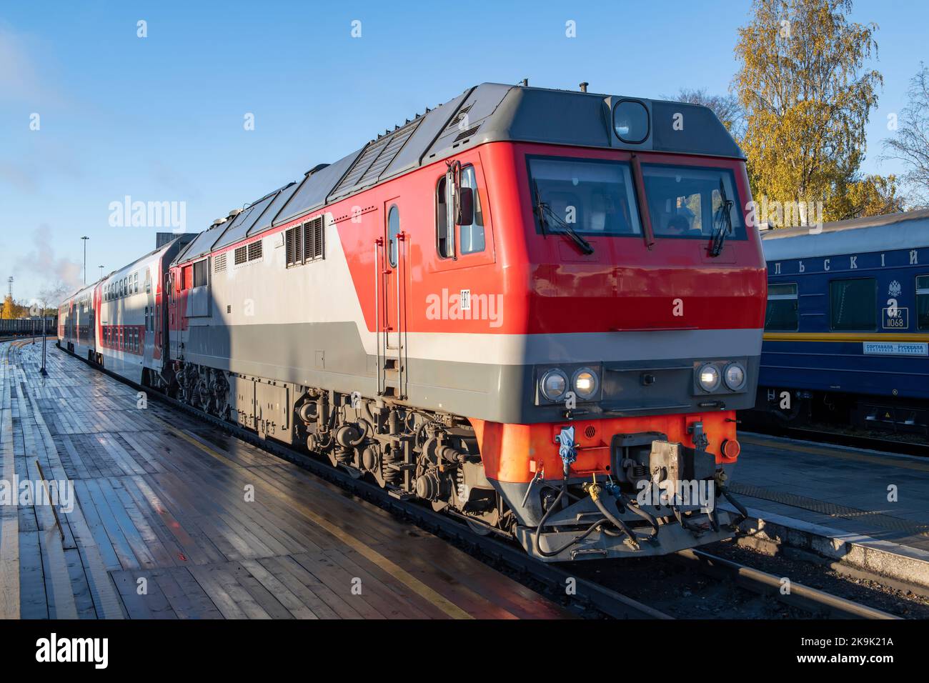 SORTAVALA, RUSSIA - 09 OTTOBRE 2022: Locomotiva diesel TEP-70BS con un moderno treno passeggeri a due piani alla piattaforma della stazione di Sortavala su un Oc Foto Stock