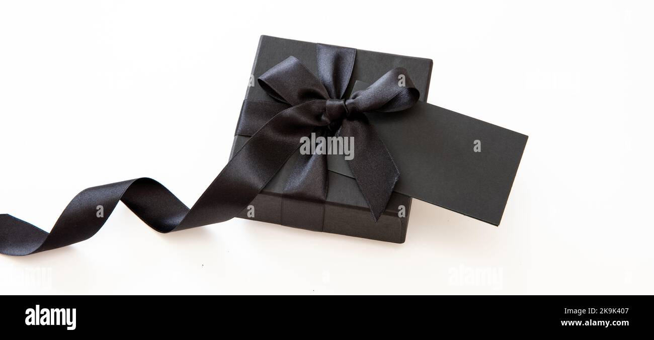 Black Friday sale e regali di Natale. Scatola regalo con nastro nero e scheda vuota isolata su sfondo bianco, Foto Stock
