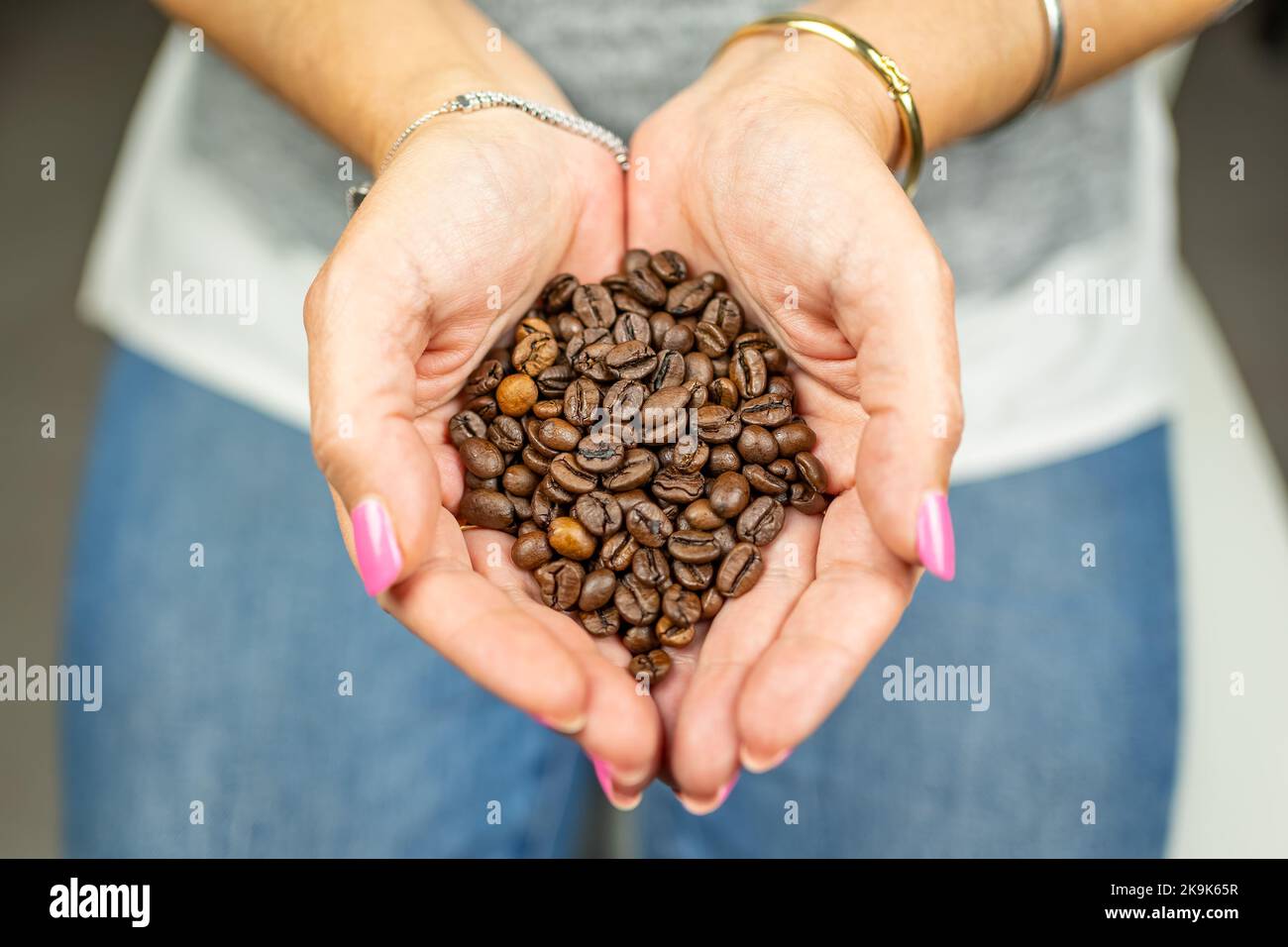 Donna che tiene in mano i chicchi di caffè arrostiti con grande aroma. Foto Stock