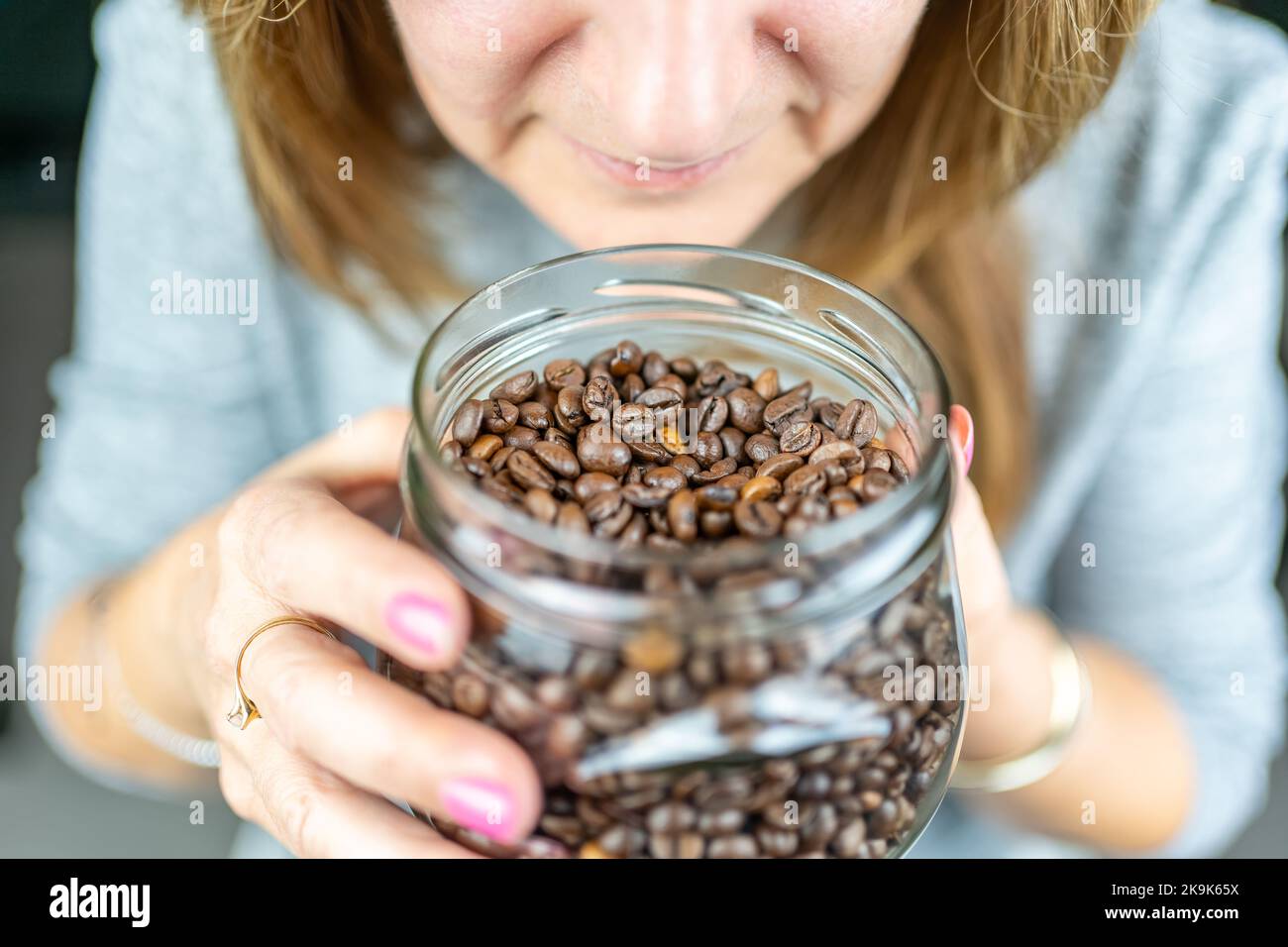 Donna che tiene in mano un vaso di vetro mentre odora l'aroma del caffè. Foto Stock