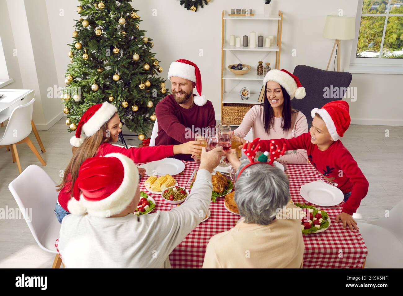 Famiglia felice che ha la cena di Natale a casa, gustando il pasto, e bevendo il succo di frutta insieme Foto Stock