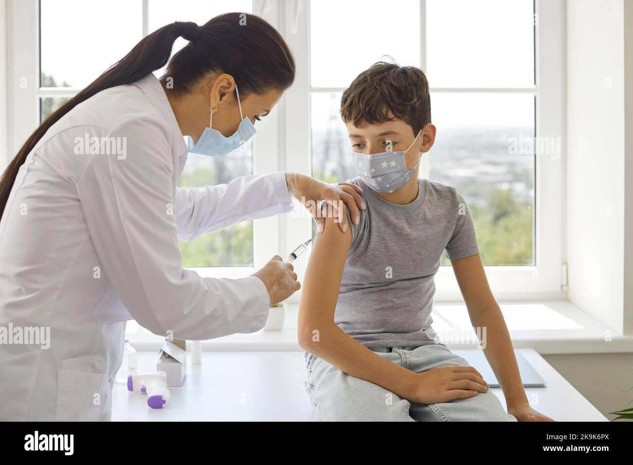 Il medico di sesso femminile effettua un'iniezione antivirale di vaccino per il bambino presteen nel centro di vaccinazione. Foto Stock