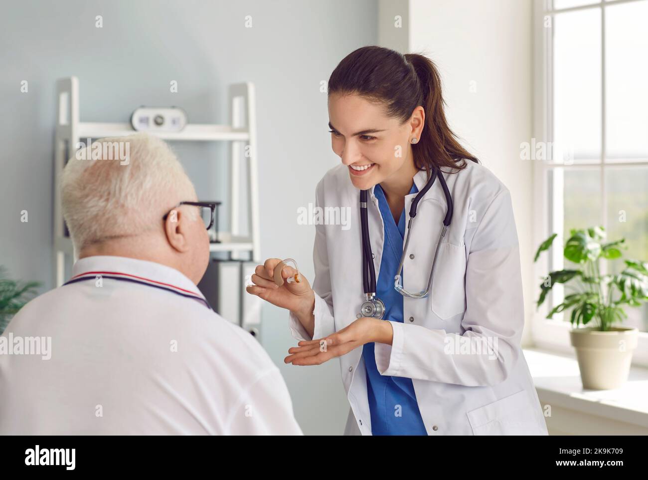 Il medico parla dei benefici e prescrive gli apparecchi acustici all'uomo anziano che è diventato duro di udito Foto Stock