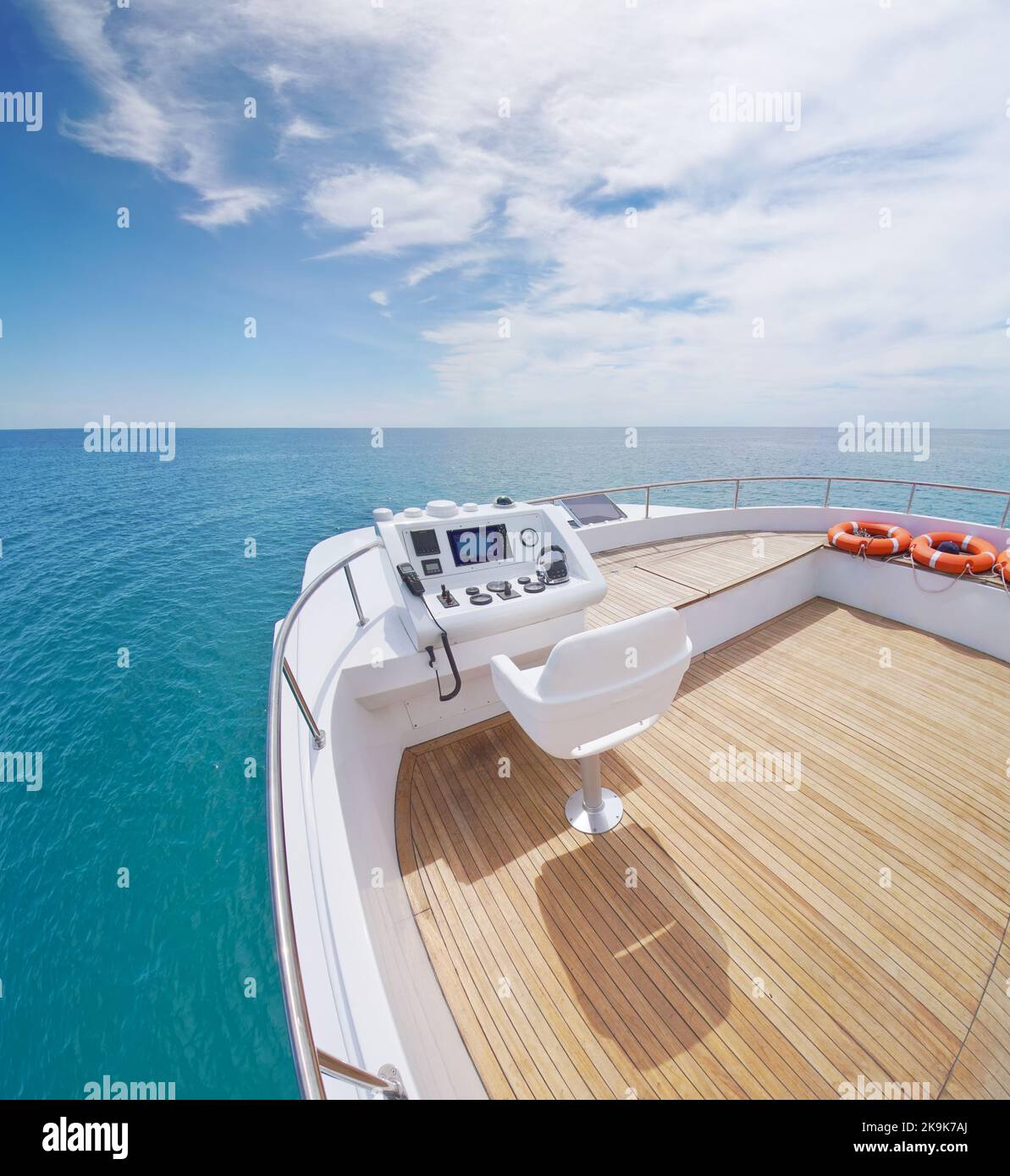 Vista dal ponte scoperto del flybridge dello yacht sulla calma acqua di mare durante il giorno. Moderno e lussuoso dotato di dispositivi di navigazione sul cruscotto. Libertà di stile di vita conc Foto Stock