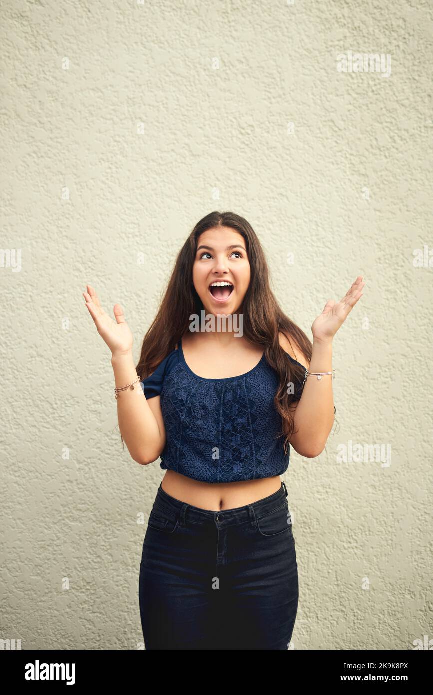 Im giovane, selvaggio, libero e solo essere me. Ritratto di una ragazza felice adolescente che si posa contro un muro fuori. Foto Stock