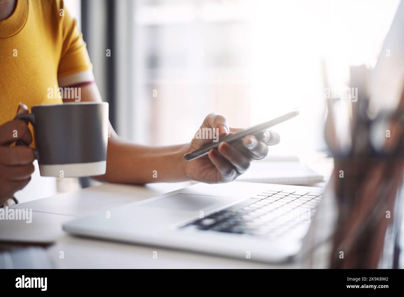 Qui per i miei clienti su qualsiasi forma di comunicazione. Primo piano di una donna designer irriconoscibile utilizzando un cellulare nel suo ufficio domestico. Foto Stock