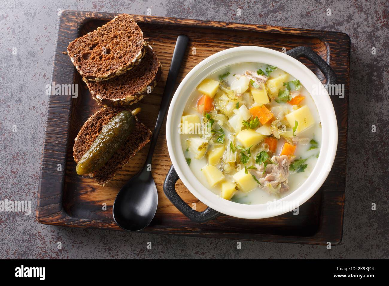 Ogorkowa Polish Sour Pickle Soup closeup sulla pentola sul vassoio di legno orizzontale vista dall'alto Foto Stock