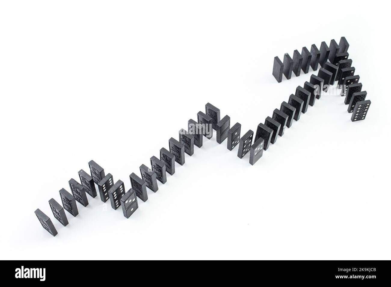 Freccia ascendente del grafico, costituita da tessere di domino nero su sfondo bianco, messa a fuoco soft in primo piano Foto Stock