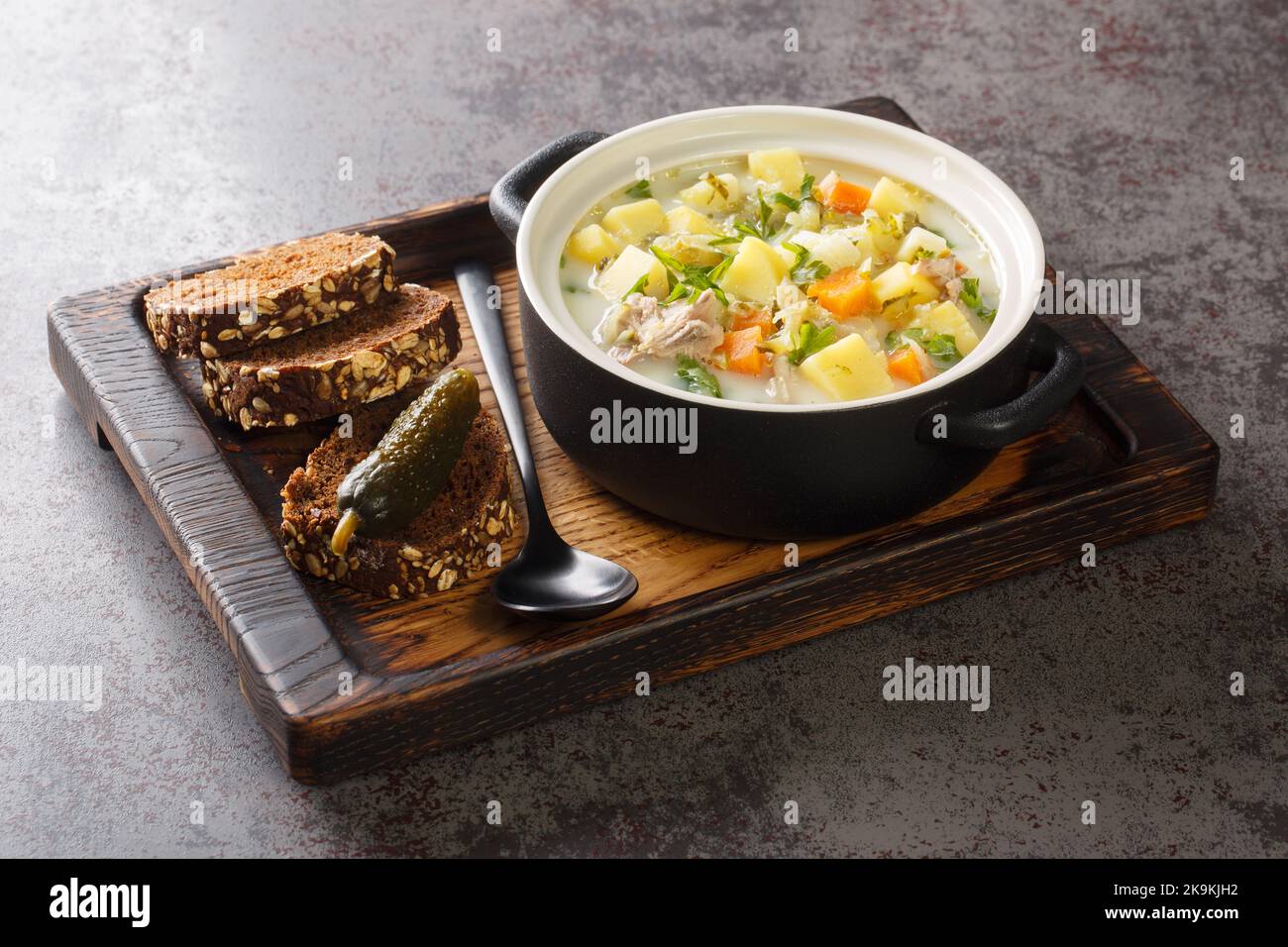 Ogorkowa Polish Sour Pickle Soup closeup sulla pentola sul vassoio di legno orizzontale Foto Stock