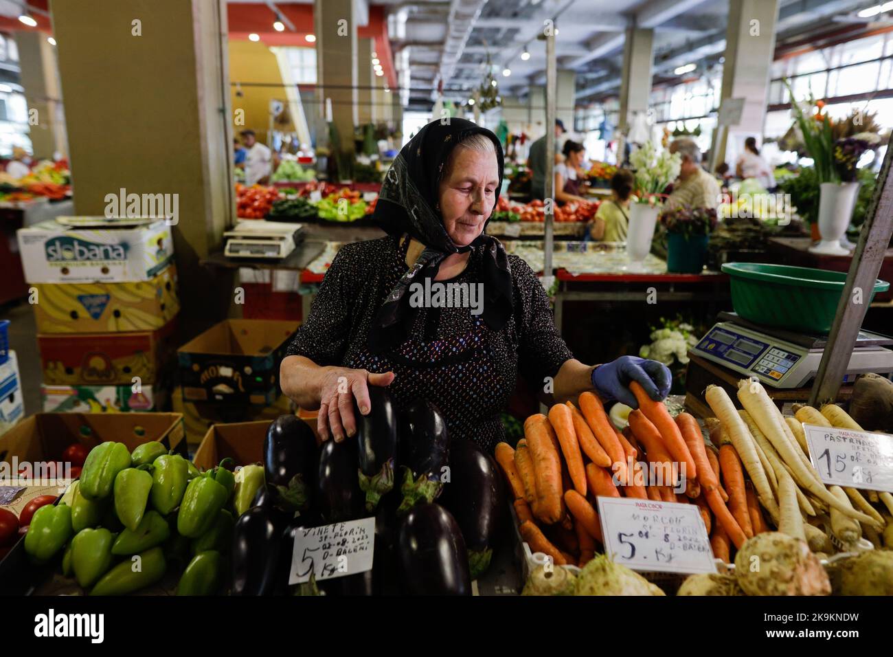 Bucarest, Romania - 4 agosto 2022: Profondità di campo poco profonda (fuoco selettivo) dettagli con una donna senior che vende ortaggi in uno stand nel mercato Obor Foto Stock