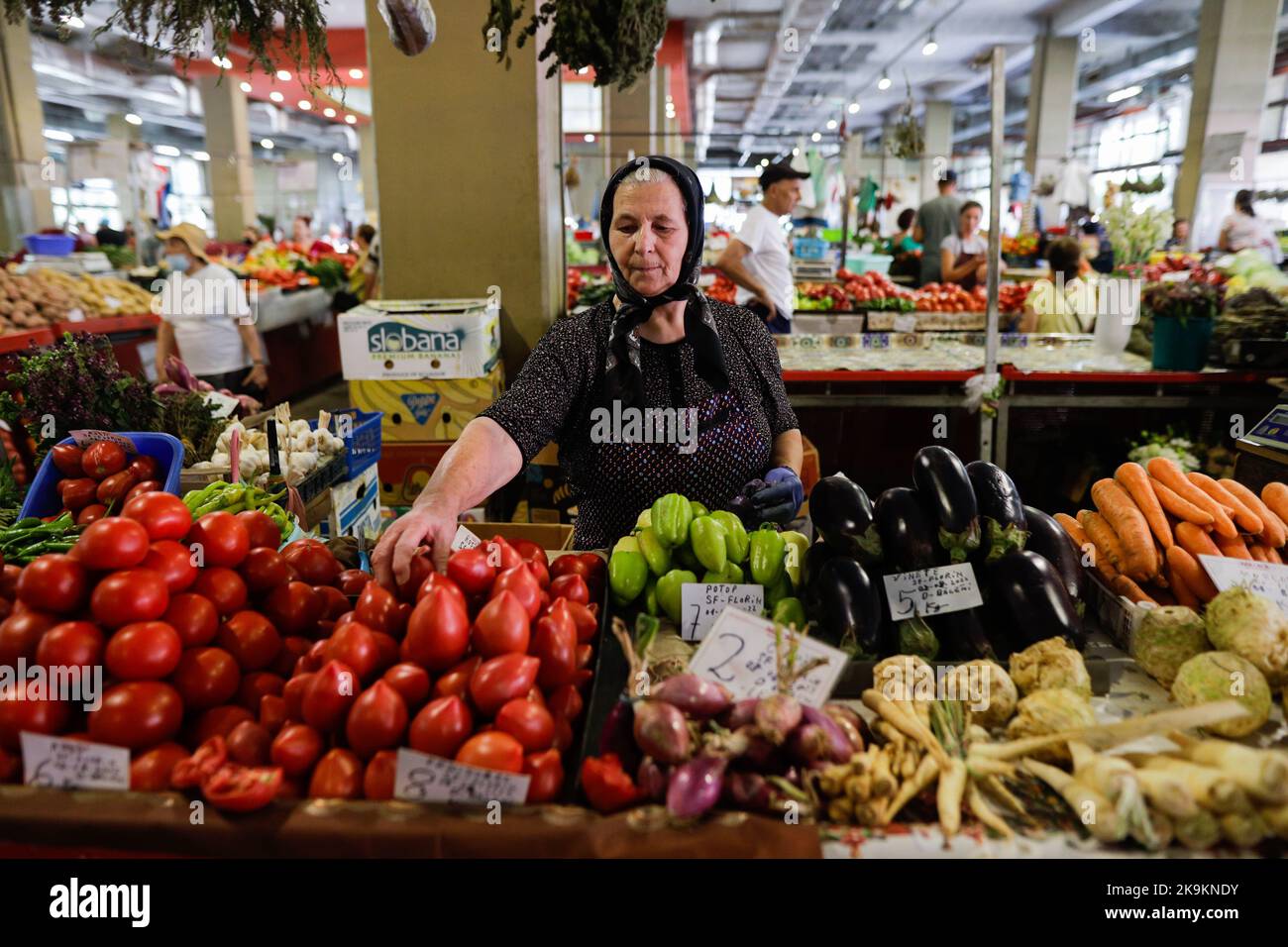 Bucarest, Romania - 4 agosto 2022: Profondità di campo poco profonda (fuoco selettivo) dettagli con una donna senior che vende ortaggi in uno stand nel mercato Obor Foto Stock