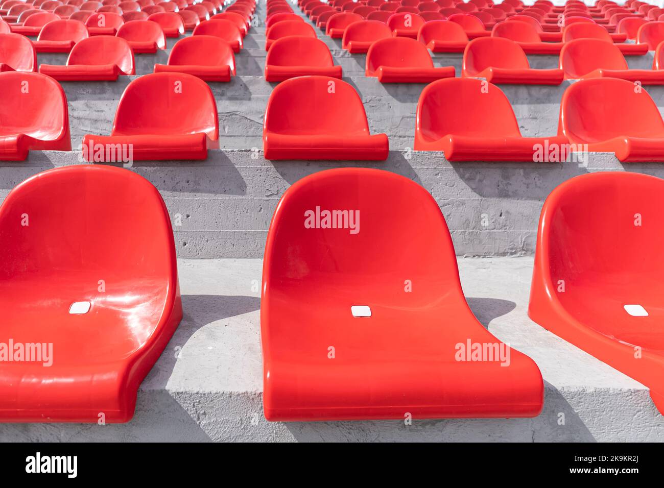 File di sedili in plastica rossa dello stadio. sedili vuoti sul podio senza persone. Foto Stock