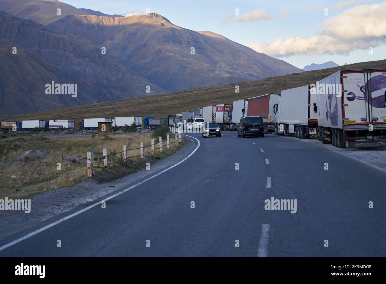 Kazbegi, Georgia - 2 ottobre 2022: Linea di camion lungo diversi chilometri sul lato della strada militare georgiana vicino a Kazbegi in attesa di croce Foto Stock