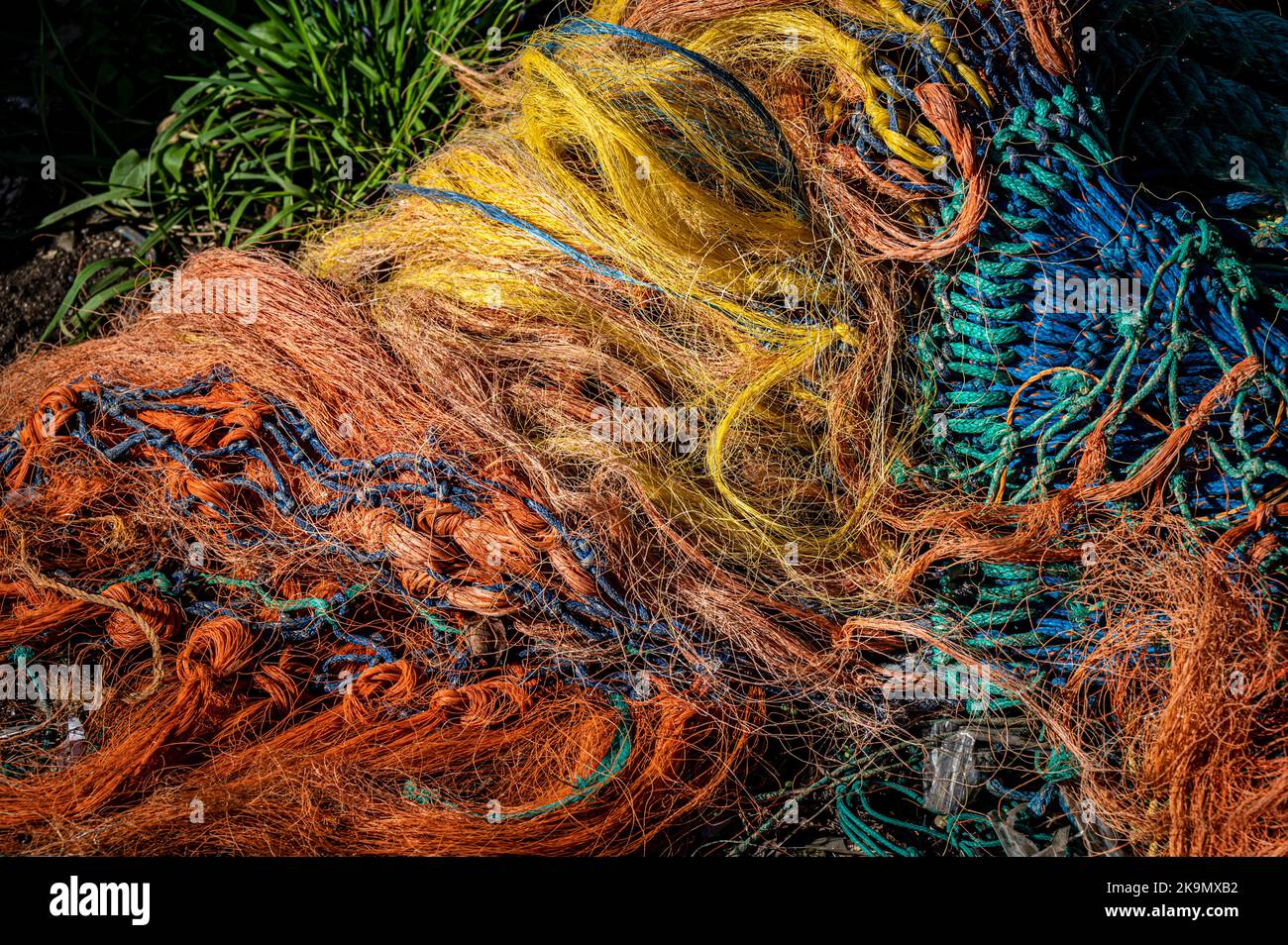 Reti da pesca colorate e aggrovigliate in un mucchio sul molo. Foto Stock