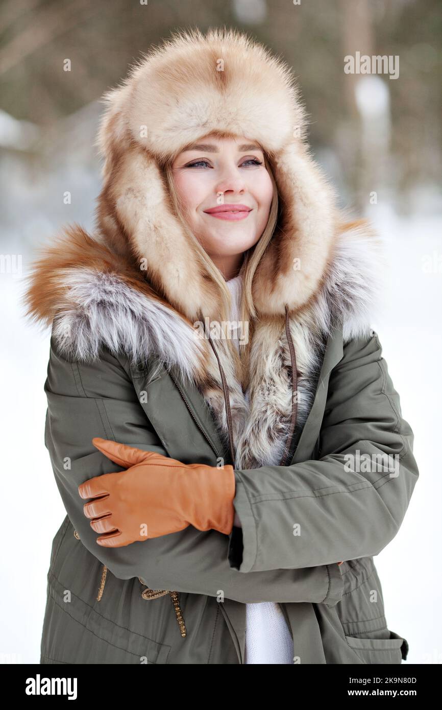 Ritratto di giovane donna in abiti caldi indossando giacca parka invernale con pelliccia, cappello in pelliccia, guanti in pelle. Abbigliamento per basse temperature Foto Stock